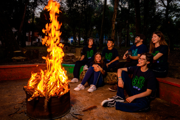 Cinco meninas estudantes com o uniforme do Colégio Marista de mãos dadas em um corredor. 